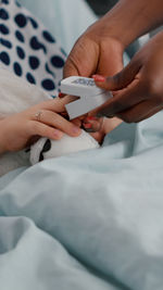 Midsection of woman using mobile phone on bed