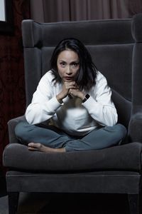 Portrait of mature woman sitting on armchair at home