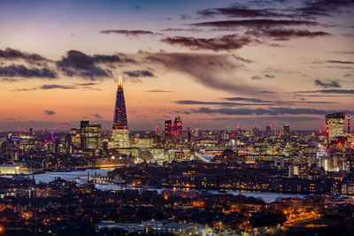 Illuminated buildings against sky during sunset in city