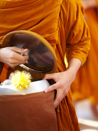 Midsection of monk holding container alms