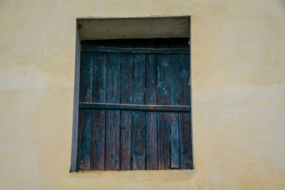 Old window closed by old wooden shutters on stone wall in castegnero, vicenza, veneto, italy