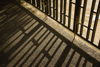 Metal fence with shadows on the concrete floor in the morning.