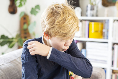 Boy coughing in arm