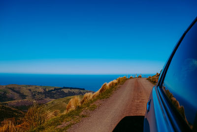 Road by sea against blue sky