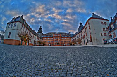 Cobblestone street amidst buildings in town against sky