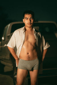 Portrait of young woman standing against black background