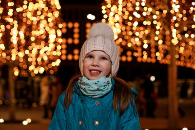 Portrait of young woman standing in city at night