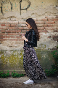 Attractive lady in dress is looking at phone outside.