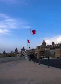 Flag by buildings against blue sky