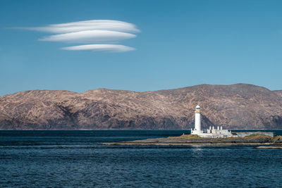 Eilean musdile lighthouse in scotland against highland mountains.  