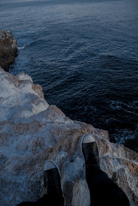 Low section of person on rock by sea