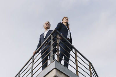 Businessman and businesswoman standing on a balcony