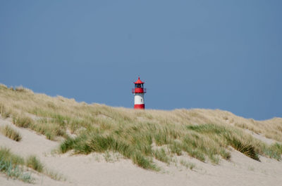 Lighthouse at beach against clear sky