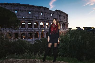 Portrait of young woman standing against built structure