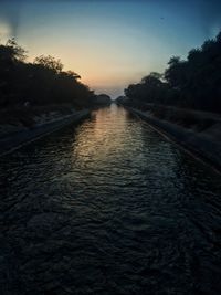 Scenic view of river against sky at sunset