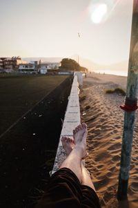 Low section of person legs against sky during sunset