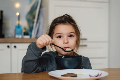 Close-up portrait of cute girl eating food at home