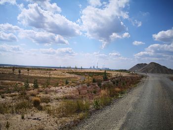 Road amidst field against sky