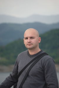 Portrait of bald man standing against mountain