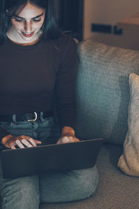 Portrait of young woman sitting on sofa at home