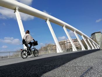 Rear view of man riding bicycle on road against sky