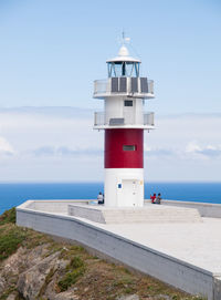 Lighthouse by sea against sky