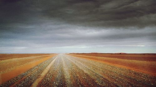 Road passing through landscape against cloudy sky