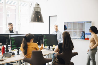 Computer hackers discussing during presentation in office