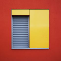 Close-up of yellow window on red wall