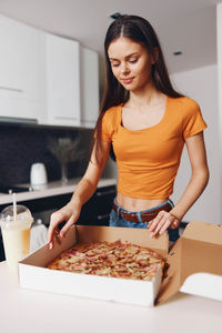 Portrait of smiling young woman preparing food at home