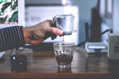 Midsection of man drinking glass on table