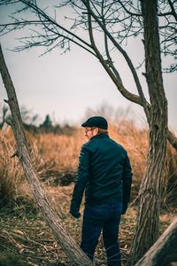 Rear view of man standing by bare tree