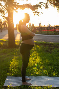 Full length of woman standing at park during sunset