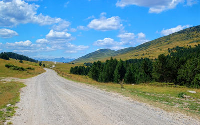 Road leading towards mountains against sky