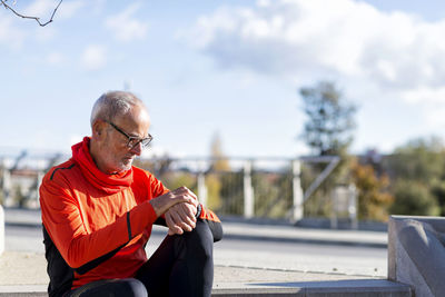 Senior man sitting on steps during sunny day