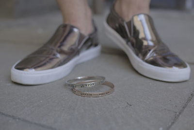 Low section of man in shiny shoes with bangles standing on boardwalk