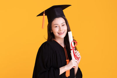 Portrait of a smiling young woman against yellow background
