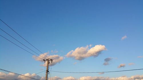Low angle view of electricity pylon against blue sky