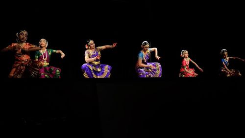 Group of people dancing against black background