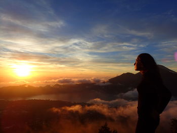 Silhouette woman standing against sky during sunset