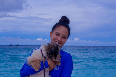 Portrait of young woman looking at sea against sky
