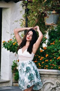 Portrait of young woman standing against plants