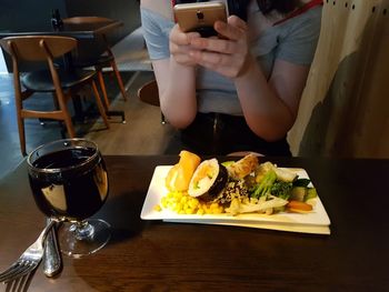 Midsection of man using smart phone in restaurant