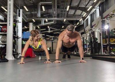 Full length of couple doing push-ups at gym