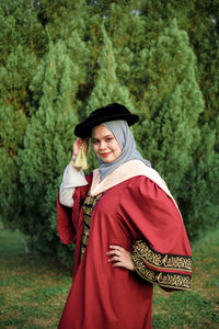 Young woman standing against red trees