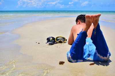 Shirtless man with scuba mask lying on sand