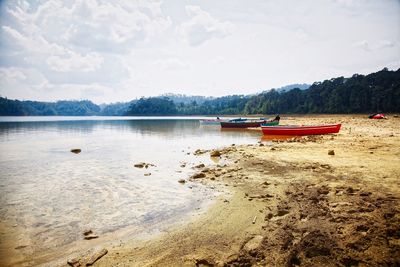 Boat moored on lake against sky