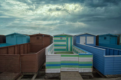 Beach huts by buildings against sky