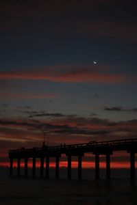 Silhouette pier over sea against sky during sunset