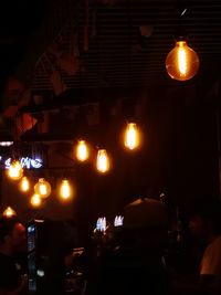 Illuminated pendant lights hanging in restaurant at night